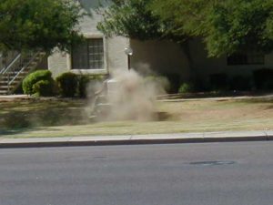 In the center of this dust cloud is a riding mower scalping the grass.
